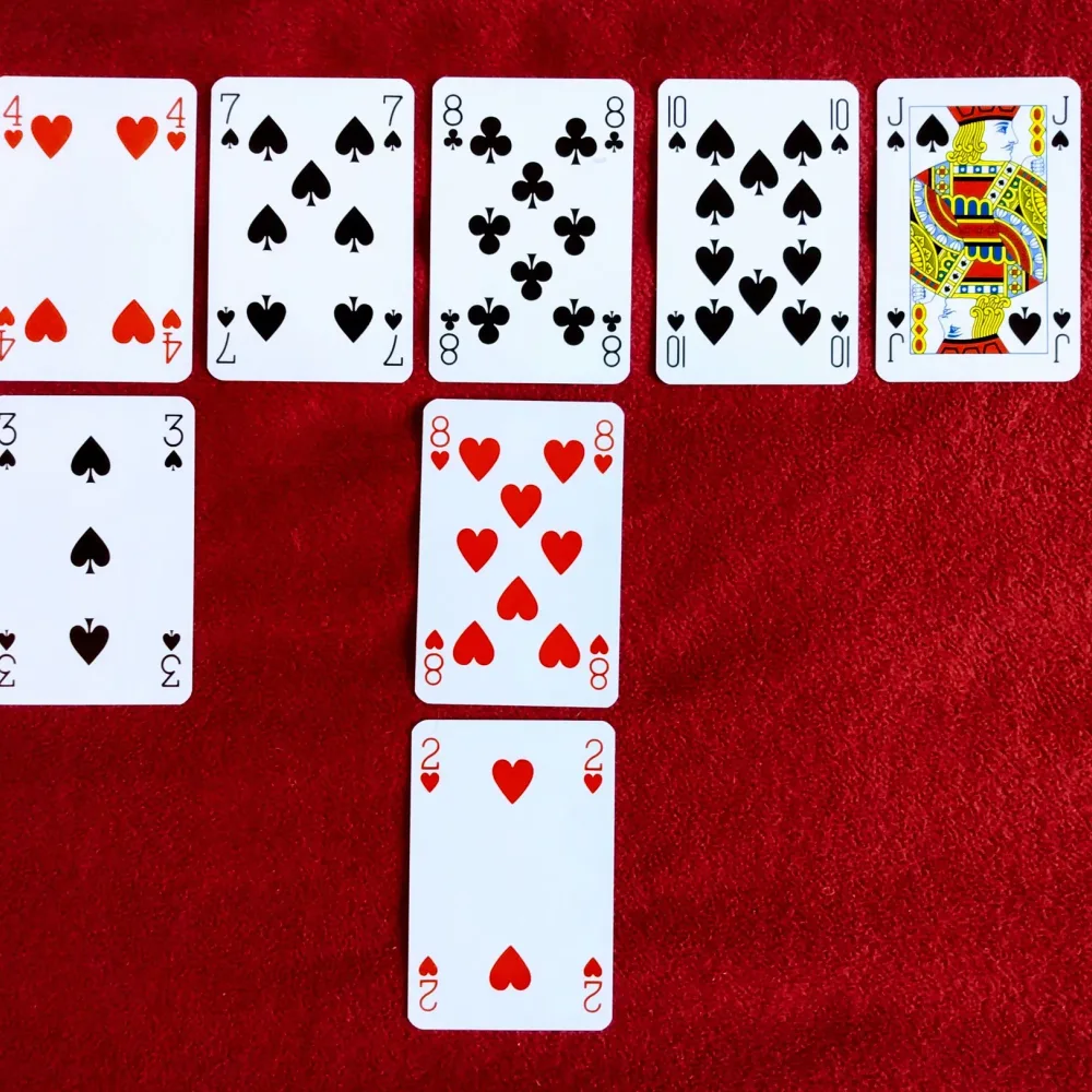 Playing cards laid out in rows on red felt